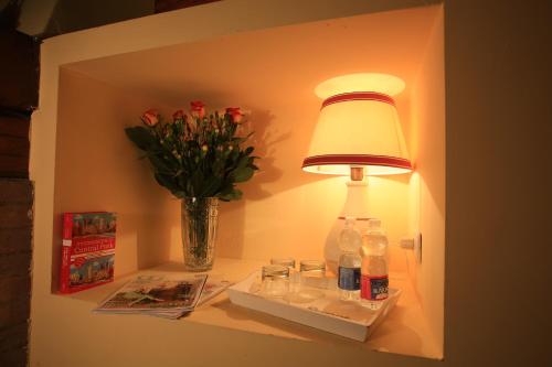 锡耶纳B&B Le Aquile的架子上的灯,有饮料和花瓶