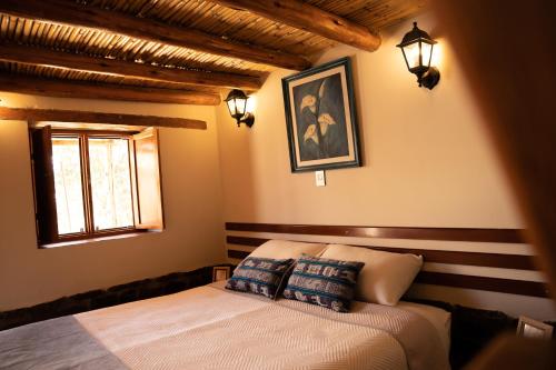 CoporaqueLodge El Portal de Qopuy的一间卧室配有带两个枕头的床和窗户