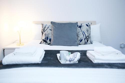 哈罗Stunning 2-Bed Apartment in Harrow的一张带两条毛巾的床和一个装有杯子的托盘