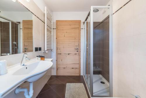 博萨迪法萨Appartamento Ciasa的浴室配有水槽、淋浴和浴缸。