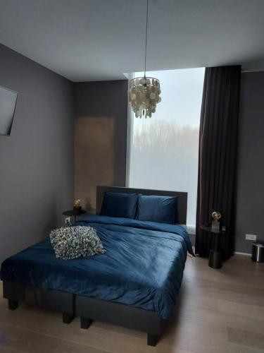 博克斯特尔Bed & Wellness Boxtel, luxe kamer met airco en eigen badkamer的一间卧室设有蓝色的床和大窗户