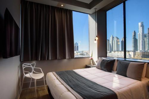 布宜诺斯艾利斯Believe Madero Hotel的卧室设有大窗户、一张床和一把椅子