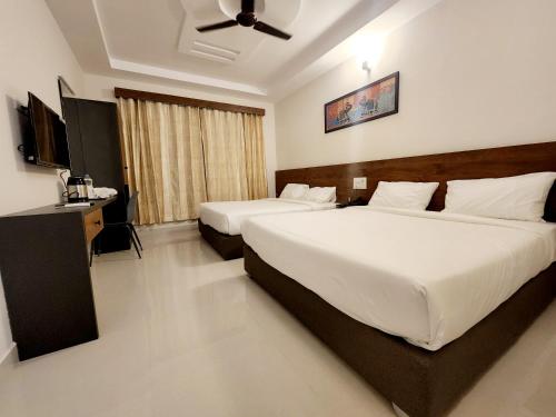 蒂鲁帕蒂HOTEL PARK RAAMA的酒店客房配有两张床和吊扇。