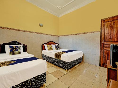三宝垄OYO Life 91677 Hotel Citra Dewi 3的一间带两张床的卧室和一台电视
