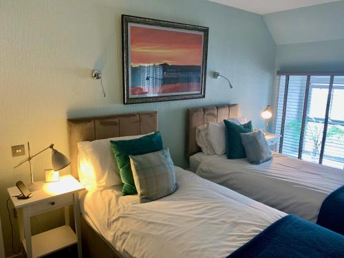 Port CharlotteLochindaal Hotel的卧室配有两张床,墙上挂着一幅画