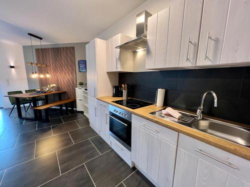 诺费尔登JUNIPRO Luxury Apartments的厨房配有白色橱柜、水槽和桌子