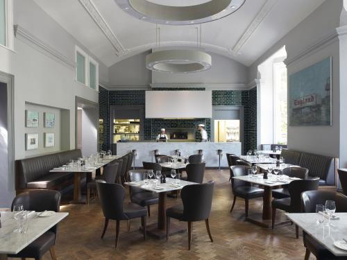 切尔滕纳姆切尔滕纳姆马尔梅森酒店的餐厅设有桌椅和白色天花板。