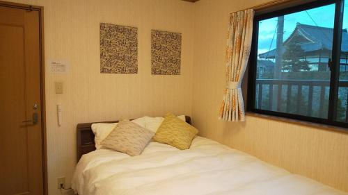 京都Guest House Nishimura - Vacation STAY 13436的一间卧室配有带两个枕头的床和窗户