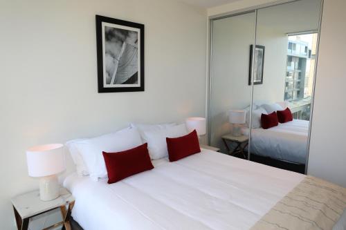 阿德莱德Realm Apartments by CLLIX的卧室配有带红色枕头的大型白色床