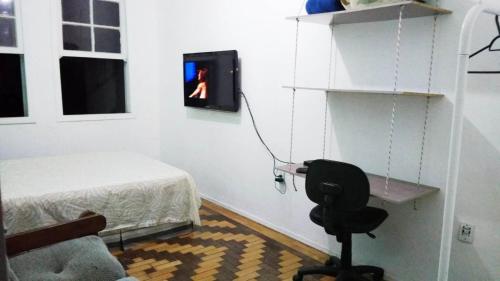 阿雷格里港Sobrado Tranquilo Centro的一间卧室配有一张床、一把椅子和电视。
