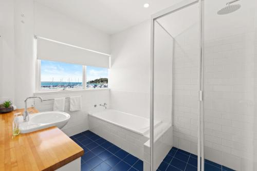 尼尔森湾鸟巢乡村别墅的白色的浴室设有浴缸和水槽。