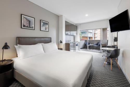 悉尼Holiday Inn & Suites Sydney Bondi Junction, an IHG Hotel的一间带白色大床的卧室和一间客厅