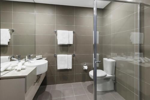 悉尼Holiday Inn & Suites Sydney Bondi Junction, an IHG Hotel的一间带两个盥洗盆、卫生间和淋浴的浴室