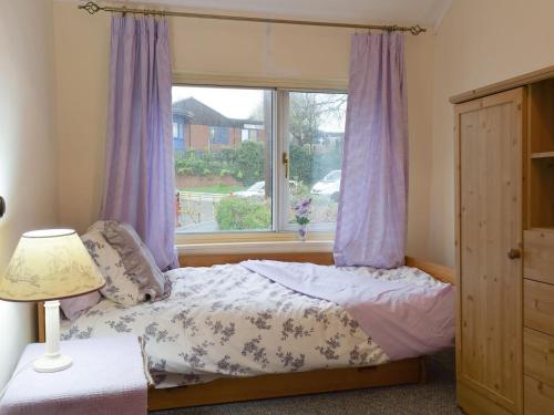 阿什比圣勒杰斯Richmond Cottage的一间卧室配有一张带紫色窗帘的床和窗户。