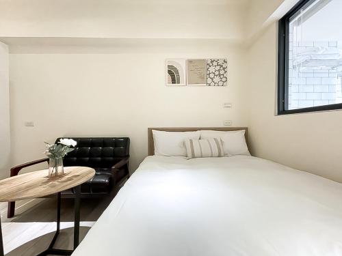 台中市旅行家 Affetto Hostel的一间卧室配有一张床、一张桌子和一个窗户。