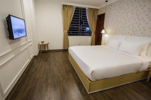 河内Khách Sạn A83Hotel的卧室配有白色的床和电视。
