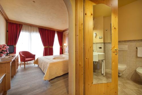 利维尼奥Hotel Valtellina的一间卧室配有一张床,浴室设有水槽