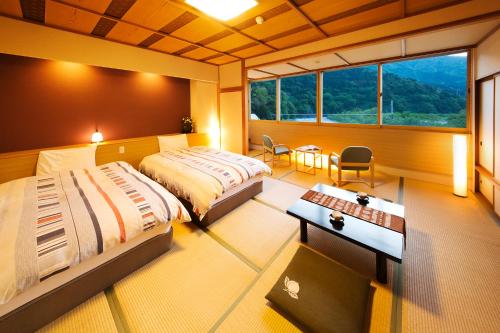 黑部市Kurobe UnazukiOnsen Togen的一间卧室设有两张床、一张桌子和一个窗口。