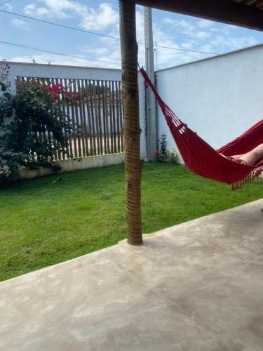 普拉杜Casa de praia Prado Ba Doces magnólias的棕榈树上的一个红色吊床,挂在院子里