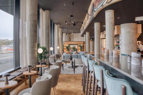 波多Smarthotel Bodø的餐厅内的酒吧,配有桌椅