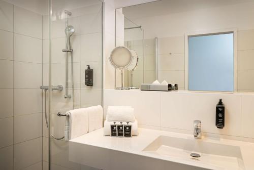 莱比锡elaya hotel leipzig city center的浴室配有盥洗盆和带镜子的淋浴