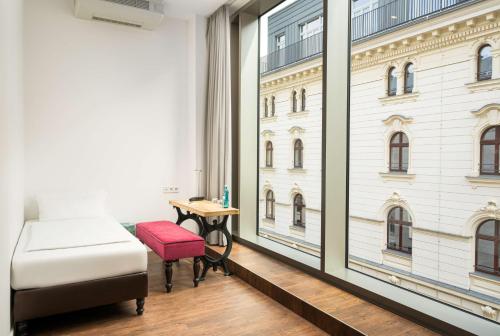 莱比锡elaya hotel leipzig city center的一间卧室配有一张床、一张桌子和一个窗户。