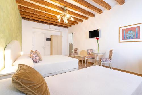 威尼斯Residenza San Silvestro的酒店客房带两张床和一张桌子以及椅子。