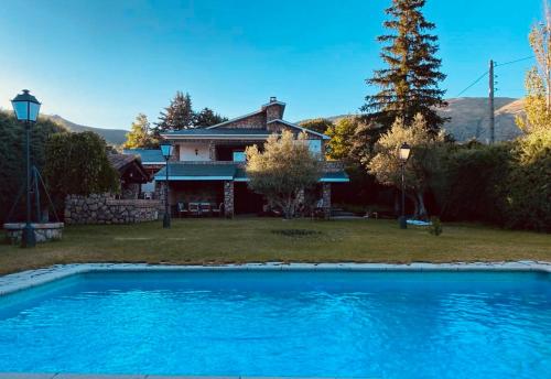BustarviejoCasa Rural LOS TINES的房子前面有蓝色的游泳池的房子