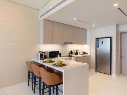 迪拜Luxury Living & Views -St Regis High Floor Suite 4 by Exclusive Holiday Homes的厨房配有带椅子和台面的酒吧