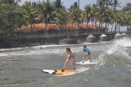 JembranaSurfers Villa and Resorts Medewi的两个女孩在水面冲浪板上挥手