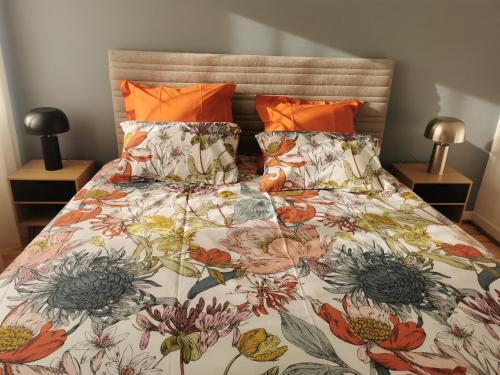 塞莱斯塔La Maison de Lucie的一张带花卉棉被和橙色枕头的床