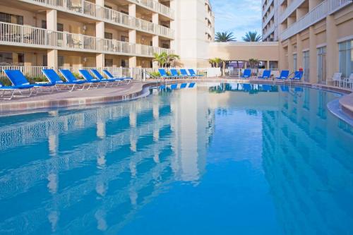 墨尔本墨尔本海滨皇冠假日酒店的一个带蓝色椅子的度假村的游泳池以及酒店