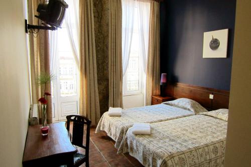 波尔图杜阿斯纳克斯旅馆的一间卧室设有两张床、一张桌子和一个窗口