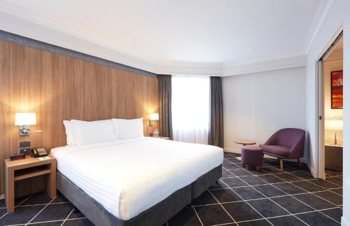 悉尼Furama Darling Harbour的配有一张床和一把椅子的酒店客房