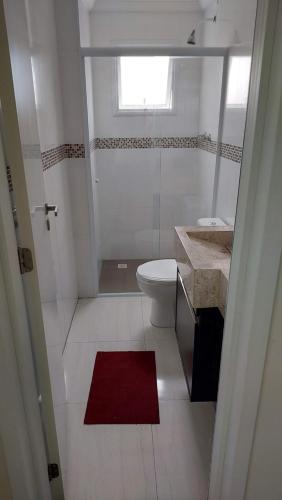 大普拉亚Apartamento Praia Grande -Canto do Forte的白色的浴室设有卫生间和红色地毯。