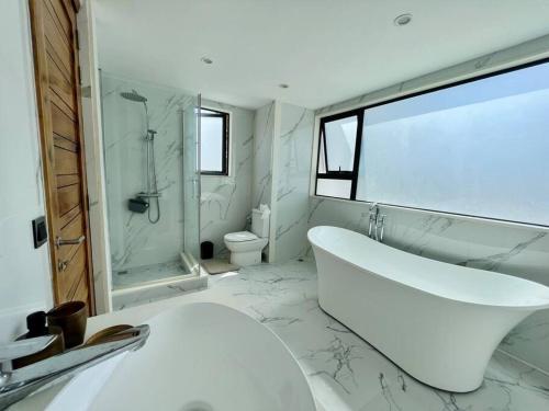 佩雷贝勒Villa Pereybère White Pearl的白色的浴室设有浴缸和水槽。