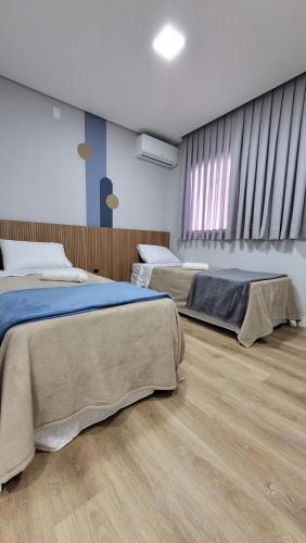 巴拉奈里奥-坎布里乌Pousada Al Mare的铺有木地板的客房内的两张床