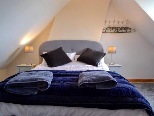 Newnham4 Greenhaye Cottages - Uk31236的一间卧室配有一张带蓝色毯子和枕头的床。