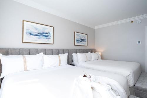温哥华苏顿普莱斯酒店的配有白色枕头的酒店客房内的两张床