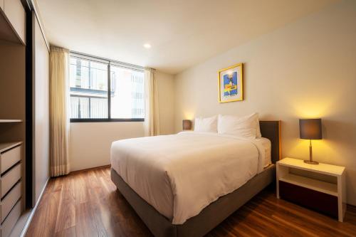 墨西哥城Capitalia - Apartments - CÉFIRO CINCO的一间卧室设有一张大床和一个窗户。