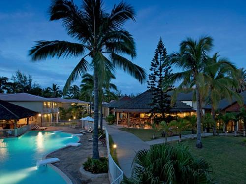 圣吉尔莱班留尼汪岛星礁度假村的夜间带游泳池和棕榈树的度假村