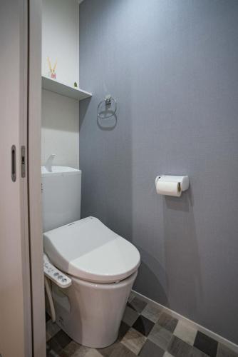 大阪震雲マンション105的浴室设有白色卫生间和一卷卫生纸。