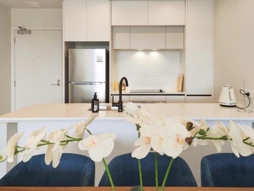 奥克兰Luxurious 2 bedroom apartment Free secure parking的厨房的柜台上摆放着白色的鲜花