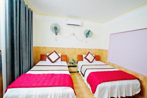 宁平New Nhat Minh HomeStay的一间卧室配有两张红色和白色床单