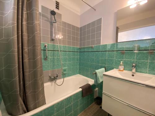 戛纳C048 Studio Spacieux proche Plages et Palais的绿色瓷砖浴室设有浴缸和水槽