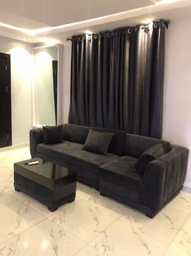 哈科特港QARAS HOUSE 3 HOTELS的客厅里一张黑色的沙发,配有黑色窗帘