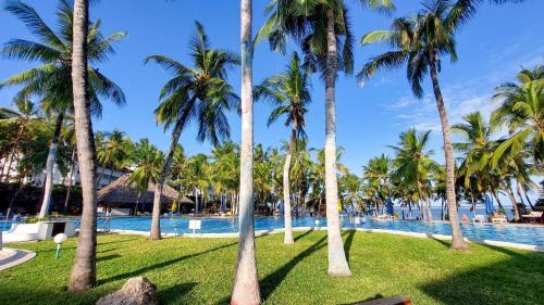 蒙巴萨PrideInn Flamingo Beach Resort & Spa Mombasa的享有棕榈树度假村的游泳池景致