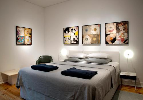 里斯本New Art Apartment的卧室配有一张大床,墙上挂有四张照片