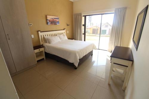 乌旺戈海滩Saints View Resort Unit 1的一间卧室配有一张床、一张书桌和一个窗户。