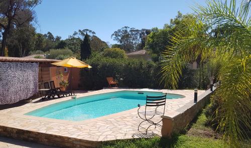 卢恰纳Chambre d'hôte Kalango proche de la plage-Piscine的庭院内一个带椅子和遮阳伞的游泳池